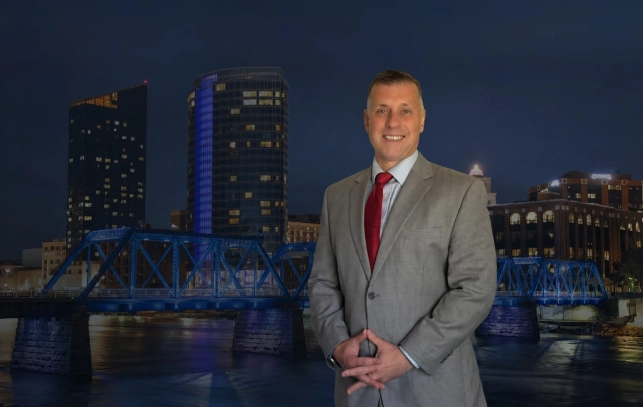 Grand Rapids Criminal Defense Lawyer Ryan Maesen Ryan Maesen criminal defense attorney in Grand Rapids MI standing in front of the Blue Bridge downtown
